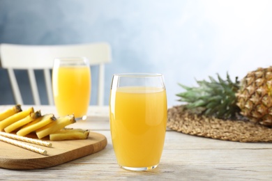 Photo of Delicious pineapple juice in glass on white wooden table
