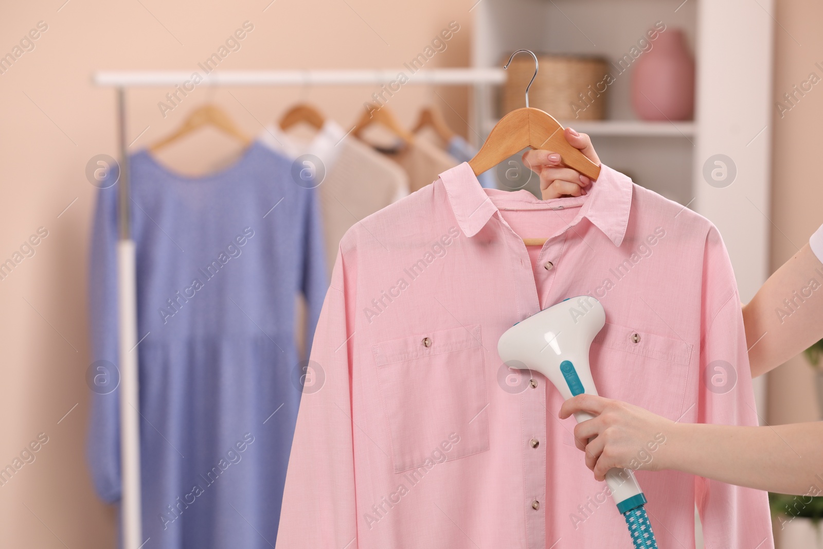 Photo of Woman steaming shirt on hanger at home, closeup. Space for text