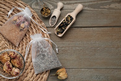 Photo of Scented sachets with dried flowers on wooden table, flat lay. Space for text