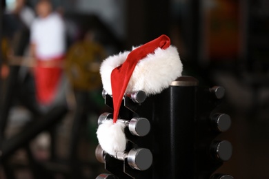 Santa Claus hat on stand with dumbbells in gym