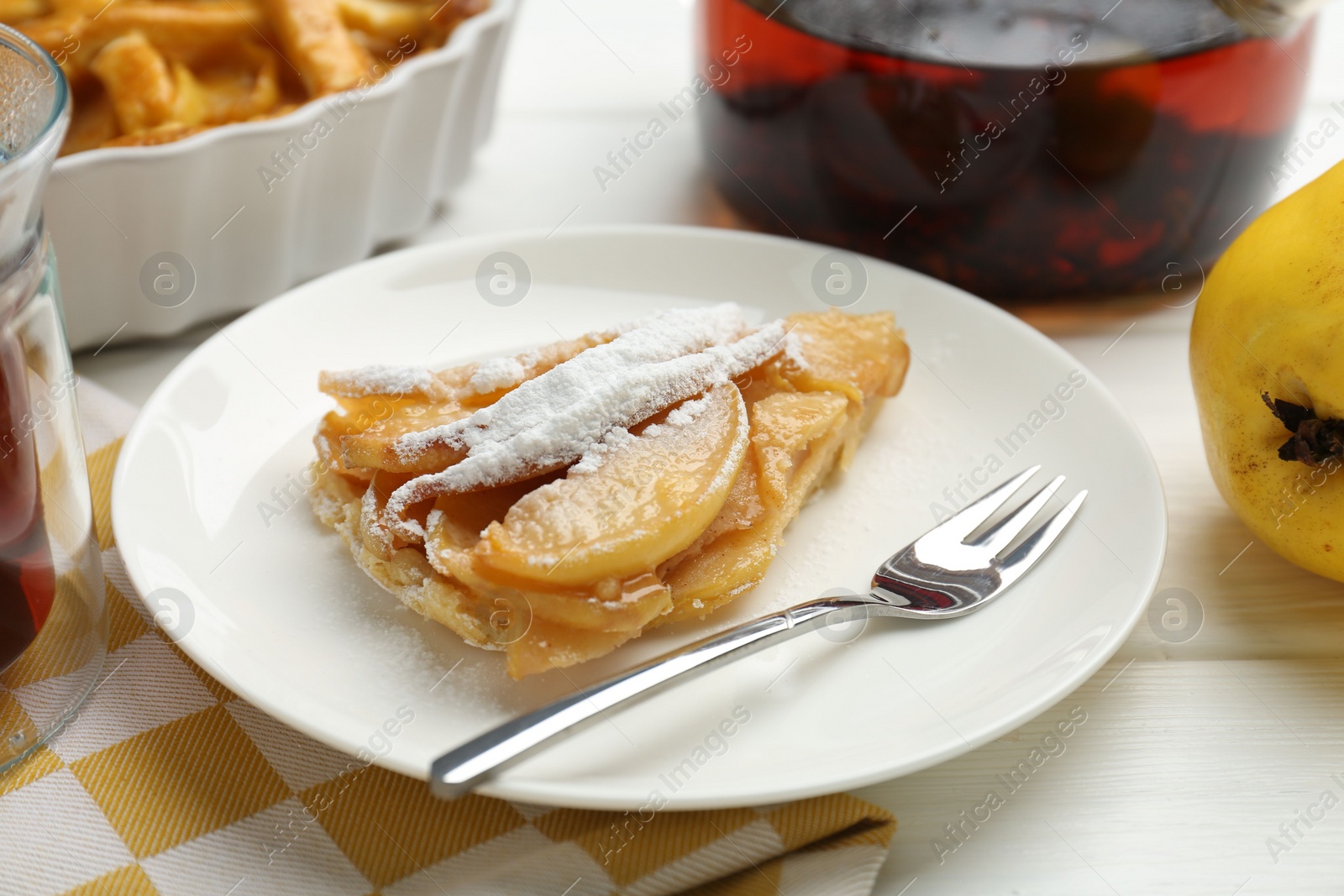 Photo of Piece of tasty homemade quince pie with powdered sugar served on white wooden table