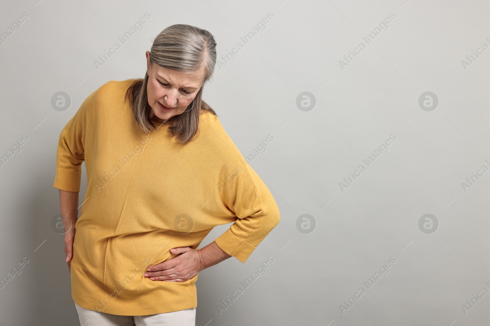 Photo of Arthritis symptoms. Woman suffering from hip joint pain on gray background, space for text