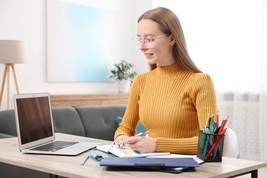 Photo of Woman taking notes at wooden table in office