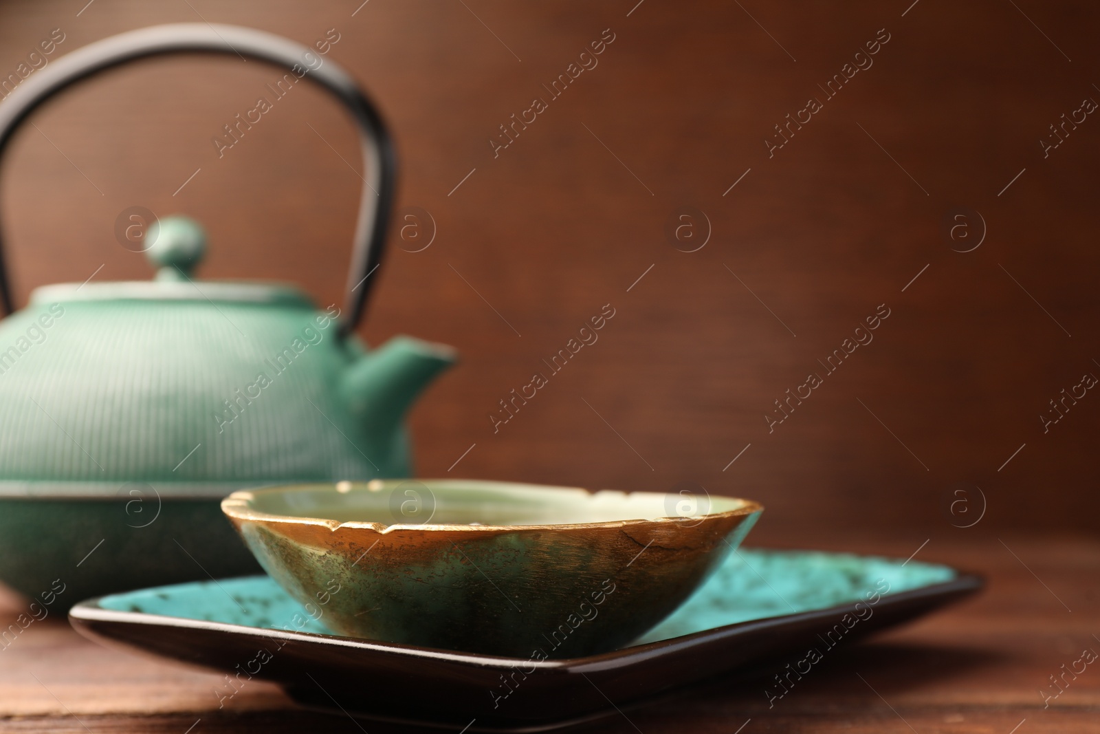 Photo of Teapot and cup of freshly brewed tea on wooden table, closeup. Traditional ceremony