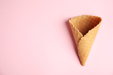 Photo of Empty wafer ice cream cone on pink background, top view. Space for text