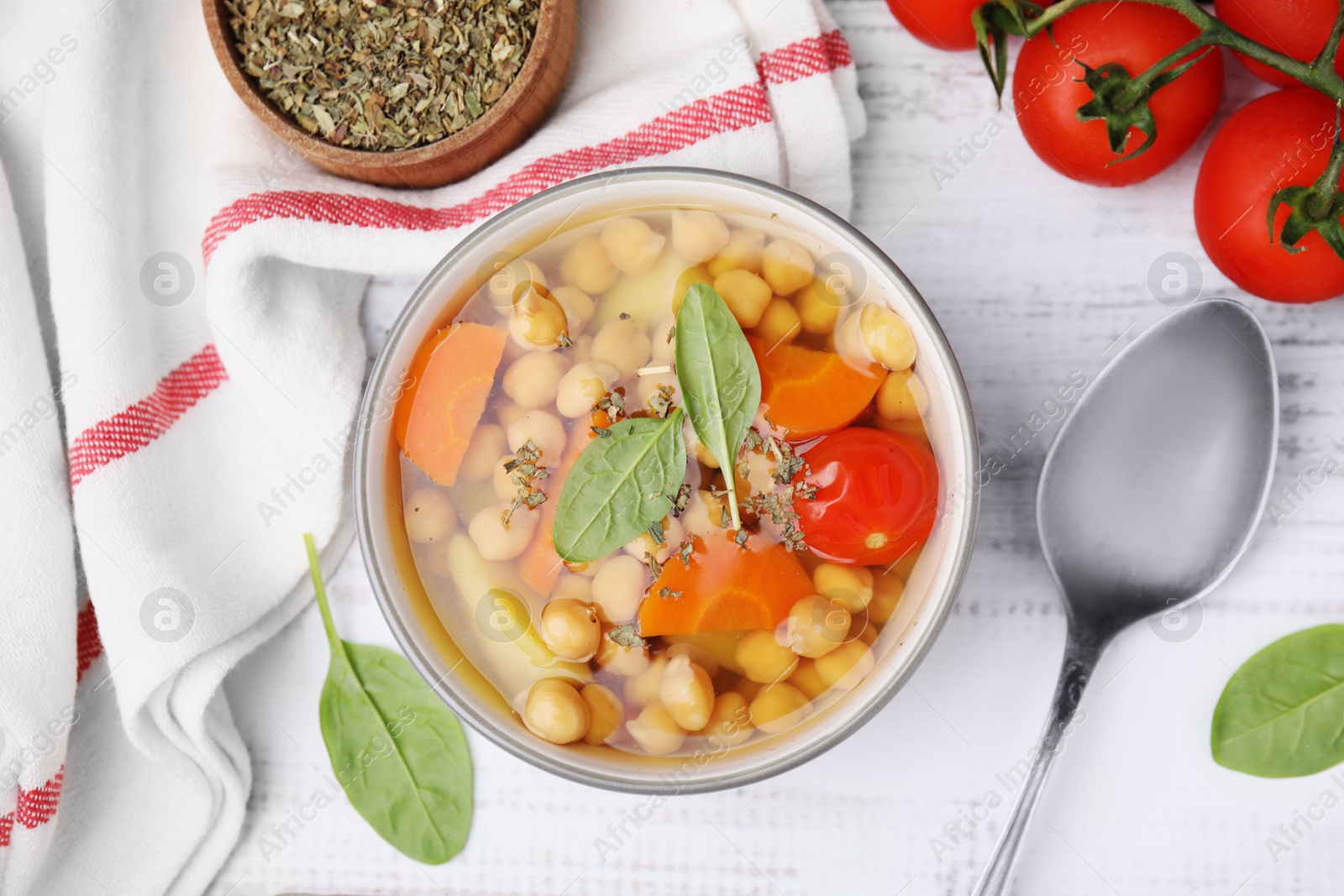 Photo of Flat lay composition of tasty chickpea soup in bowl and spices served on white wooden table