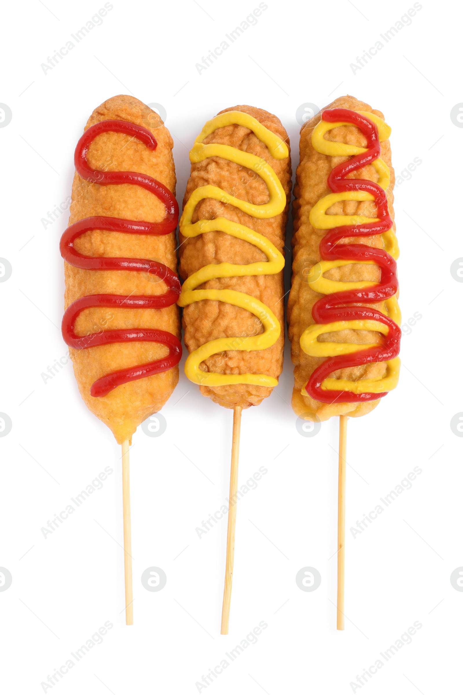 Photo of Delicious deep fried corn dogs with sauces on white background, top view