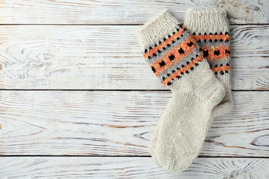 Photo of Warm knitted socks on white wooden background, flat lay. Space for text