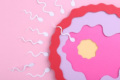Photo of Fertilization concept. Sperm cells swimming towards egg cell on pink background, top view