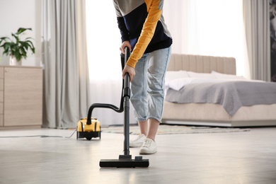 Young woman using vacuum cleaner at home, closeup