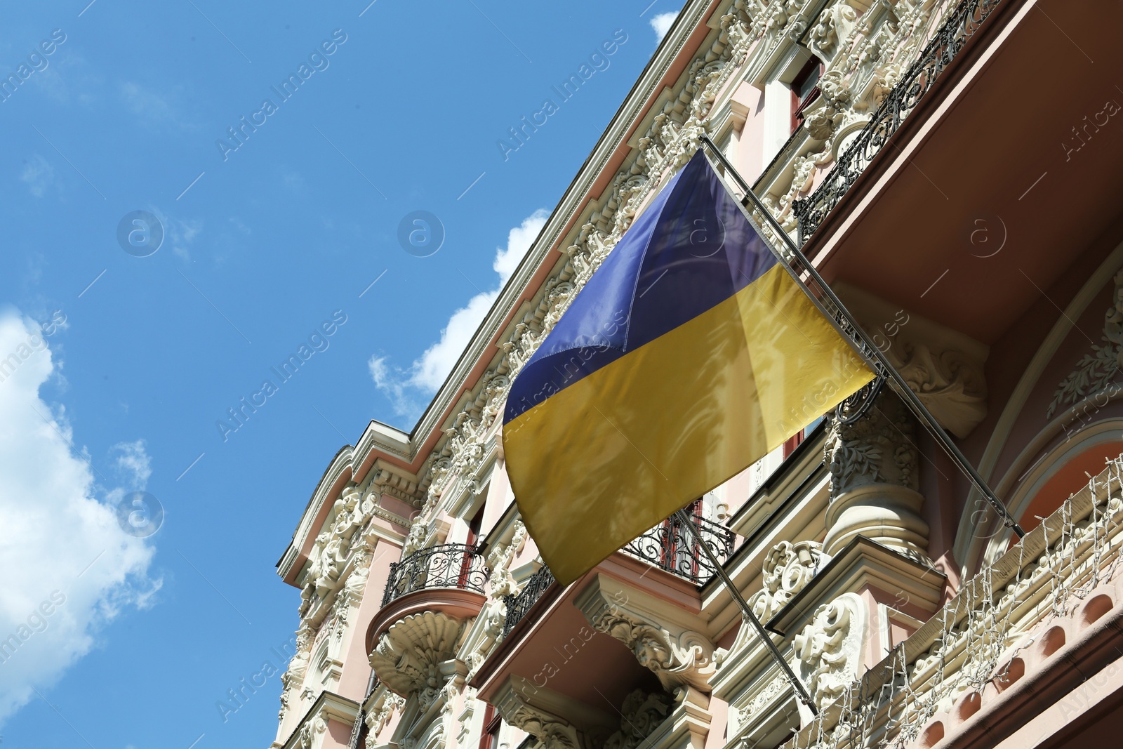 Photo of Ukrainian flag on building facade against blue sky, low angle view. Space for text