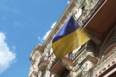 Ukrainian flag on building facade against blue sky, low angle view. Space for text