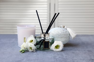 Reed diffuser, scented candle, box and eustoma flowers on gray marble table