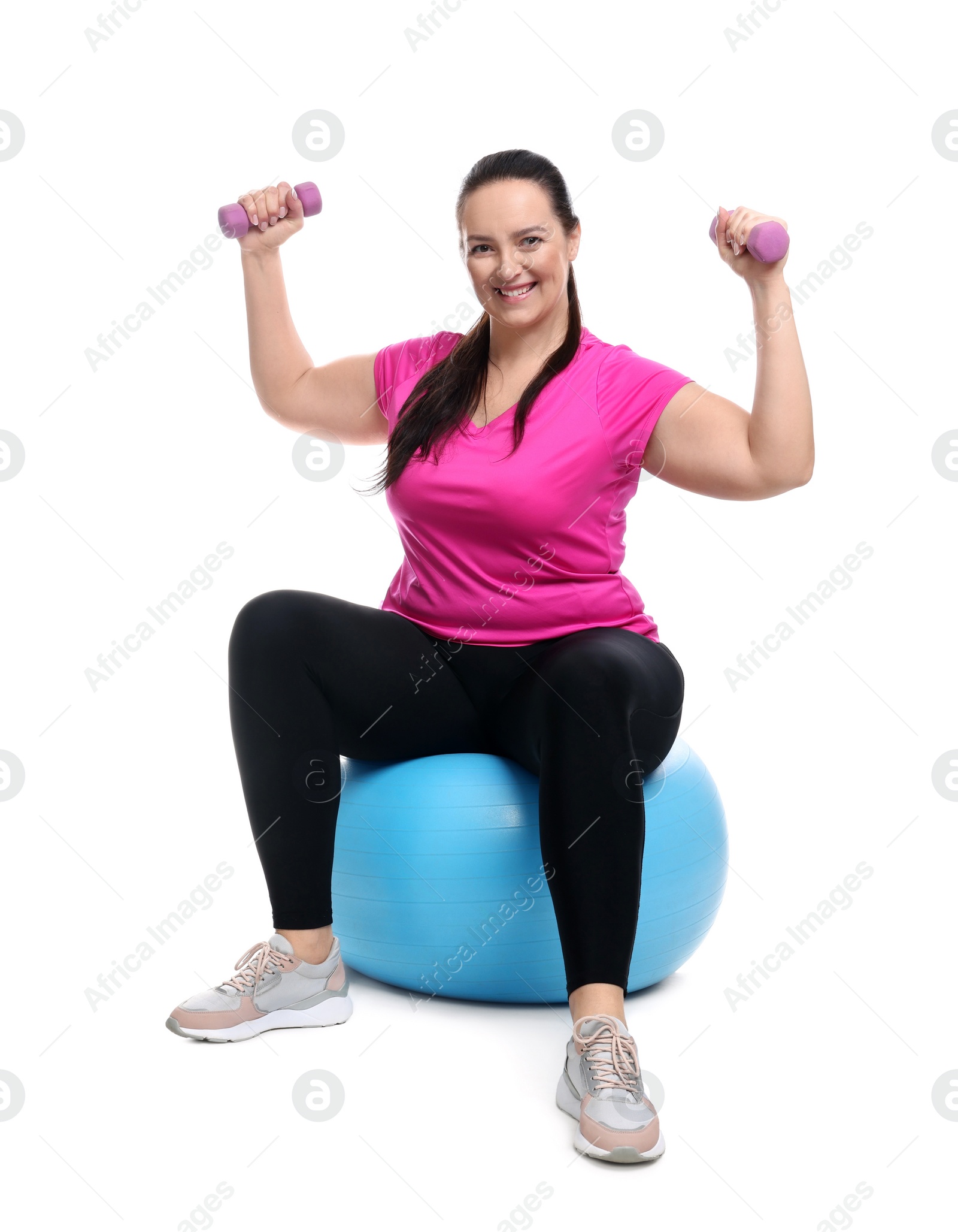 Photo of Happy overweight woman with dumbbells sitting on fitness ball against white background