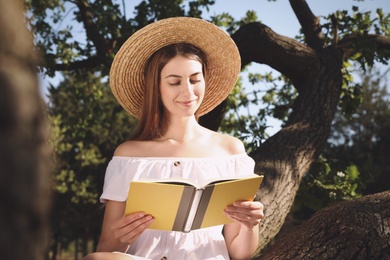 Young woman reading book on tree in park