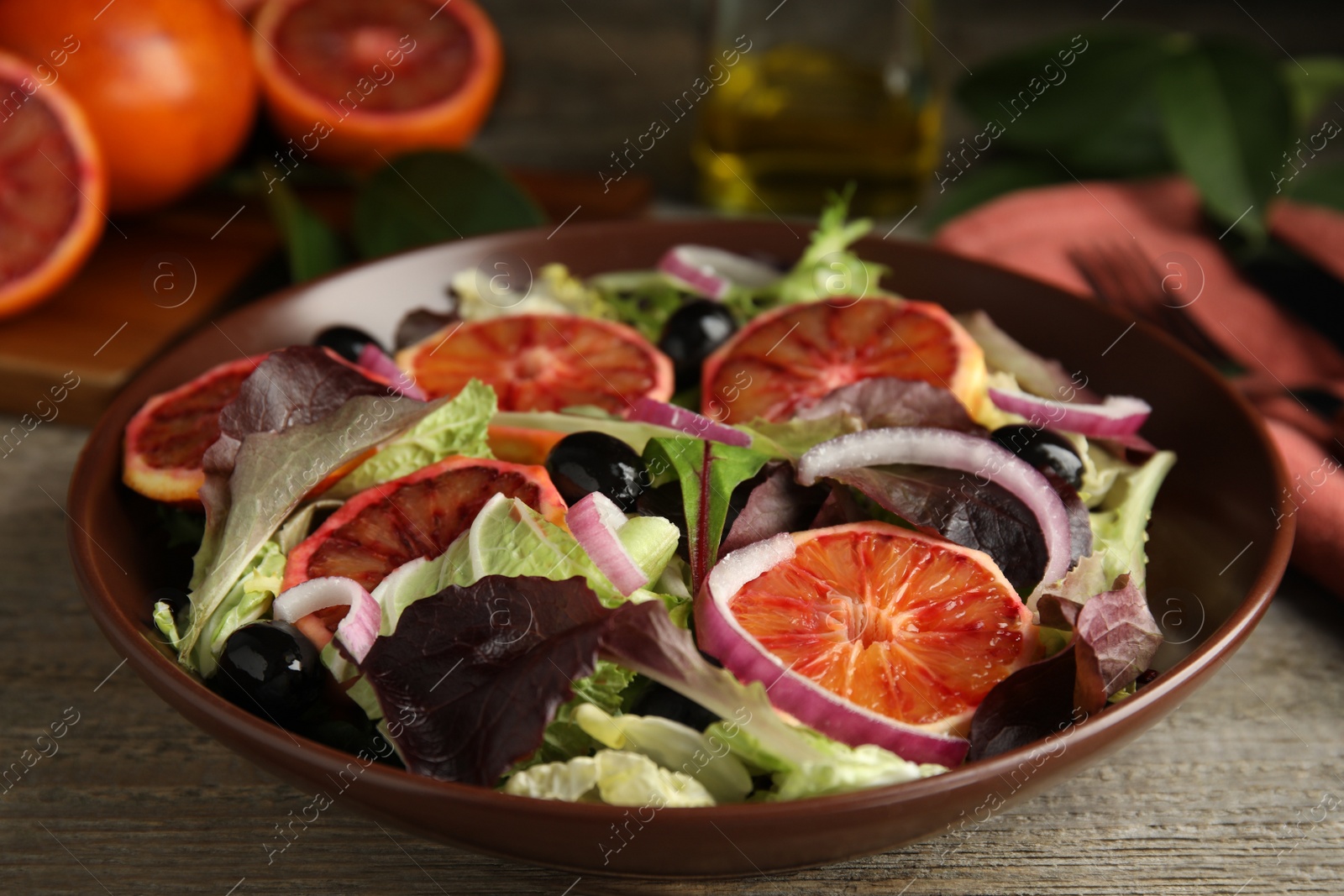 Photo of Bowl of delicious sicilian orange salad on wooden table, closeup