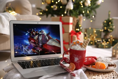 Photo of MYKOLAIV, UKRAINE - DECEMBER 25, 2020: Laptop displaying Christmas Chronicles movie at home. Cozy winter holidays atmosphere
