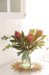 Bouquet with beautiful protea flowers on countertop in kitchen. Interior design