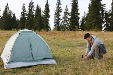 Photo of Man setting up grey camping tent outdoors