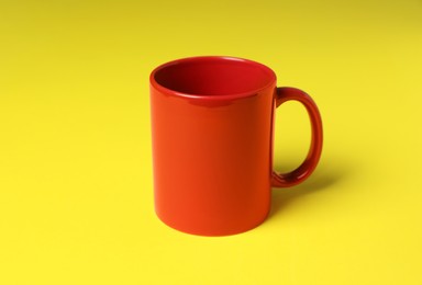 Photo of One red ceramic mug on yellow background