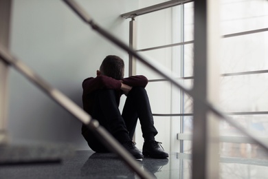 Upset preteen boy sitting on staircase indoors