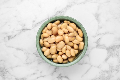 Photo of Bowl of canned kidney beans on white marble table, top view