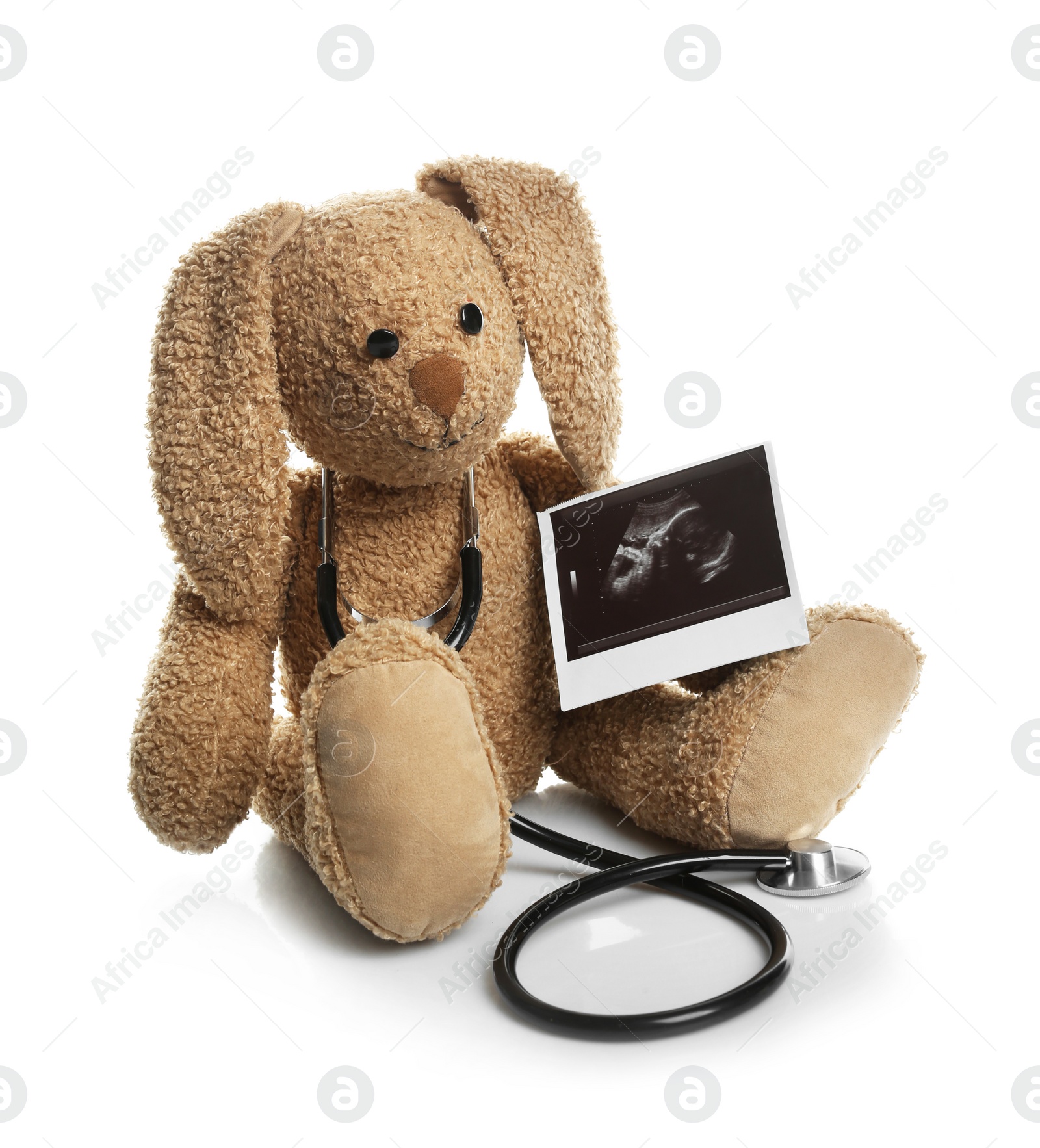 Photo of Ultrasound photo of baby and toy rabbit on white background. Concept of pregnancy