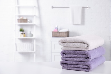 Stack of fresh towels on table in bathroom. Space for text