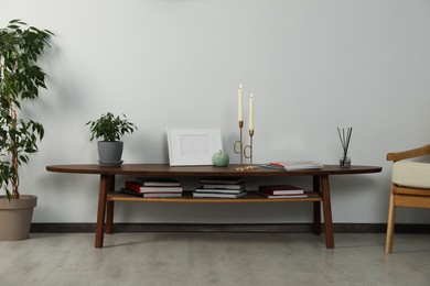 Photo of Wooden table with decorative elements near light wall in room. Interior design