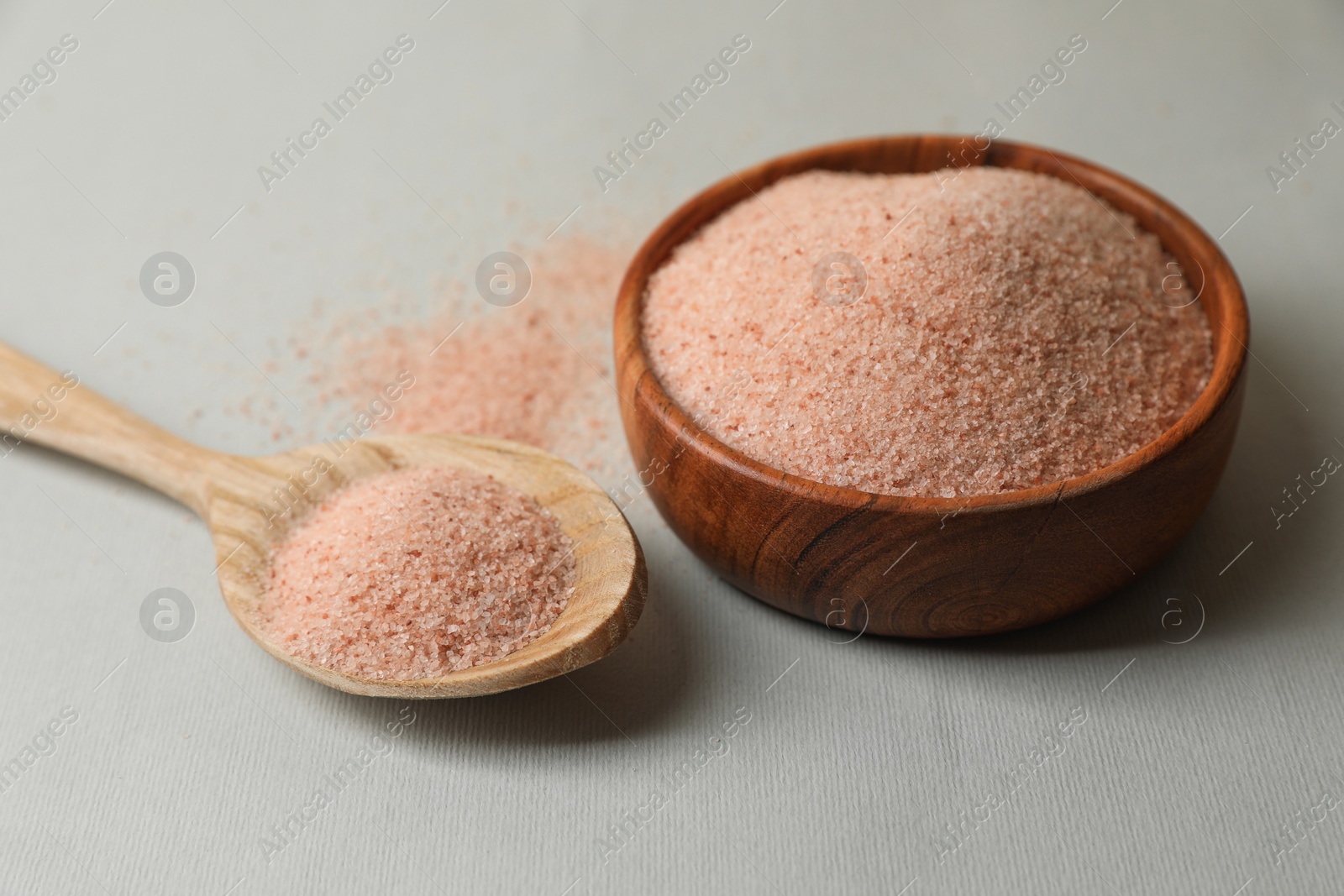 Photo of Himalayan salt in bowl and spoon on grey background