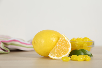 Photo of Fresh lemon and tasty small drops on wooden table