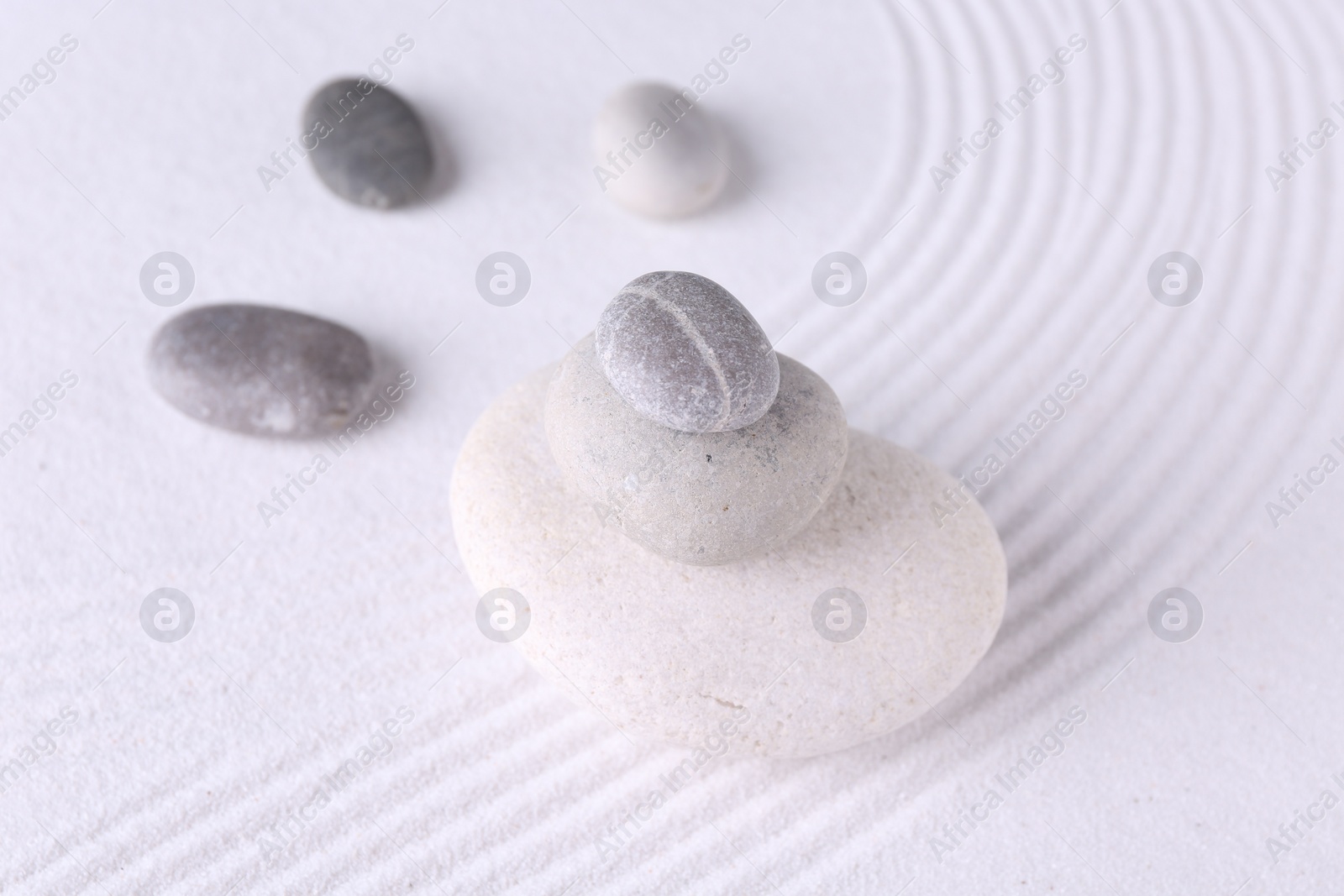 Photo of Zen garden stones on white sand with pattern