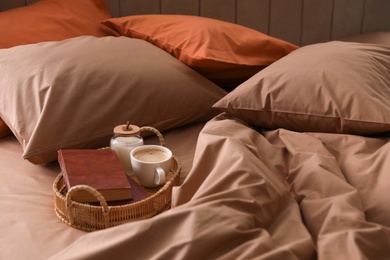 Photo of Cup of hot coffee and books on bed with stylish linens