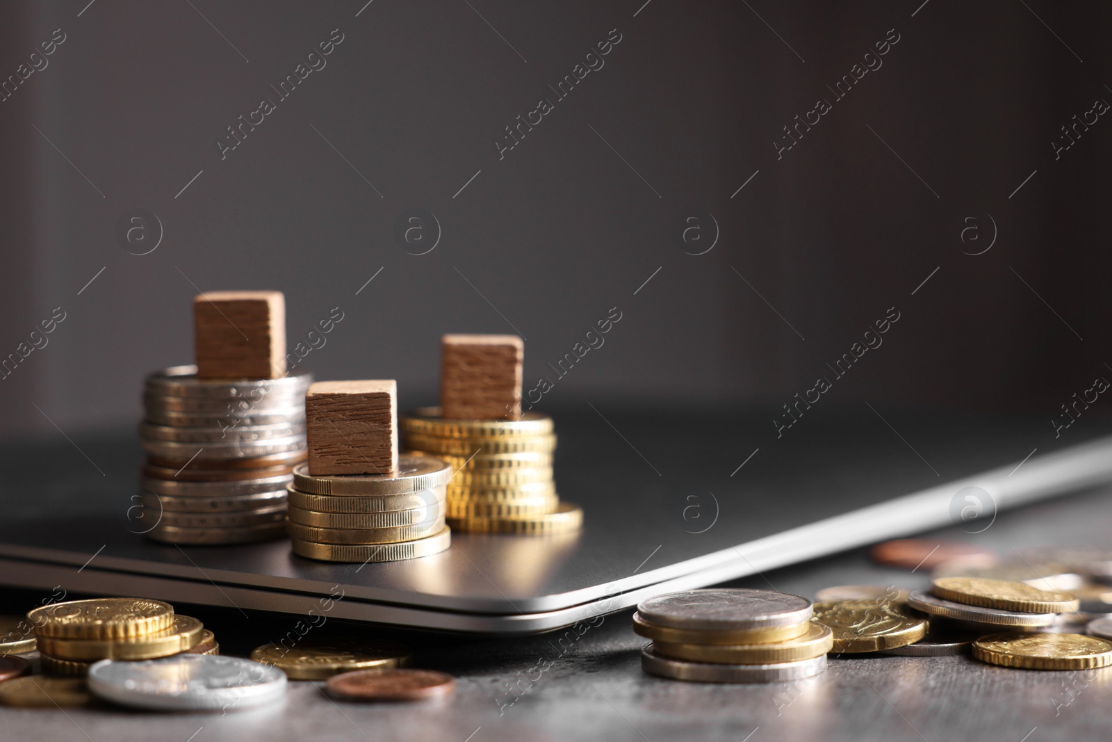 Photo of Taxes. Wooden cubes, laptop and coins at grey table, space for text