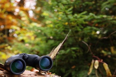 Photo of Binoculars on log in forest, space for text