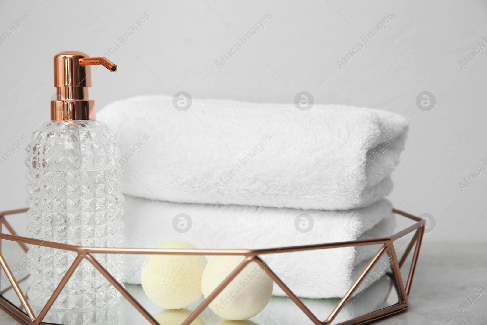 Photo of Tray with towels and toiletries on table against grey background