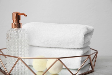 Tray with towels and toiletries on table against grey background