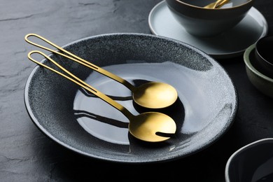 Photo of Set of clean tableware on black table, closeup