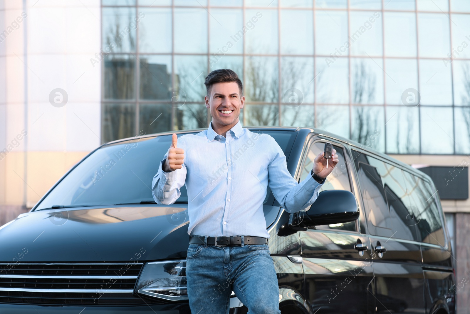 Photo of Man with key near car on city street. Buying new auto