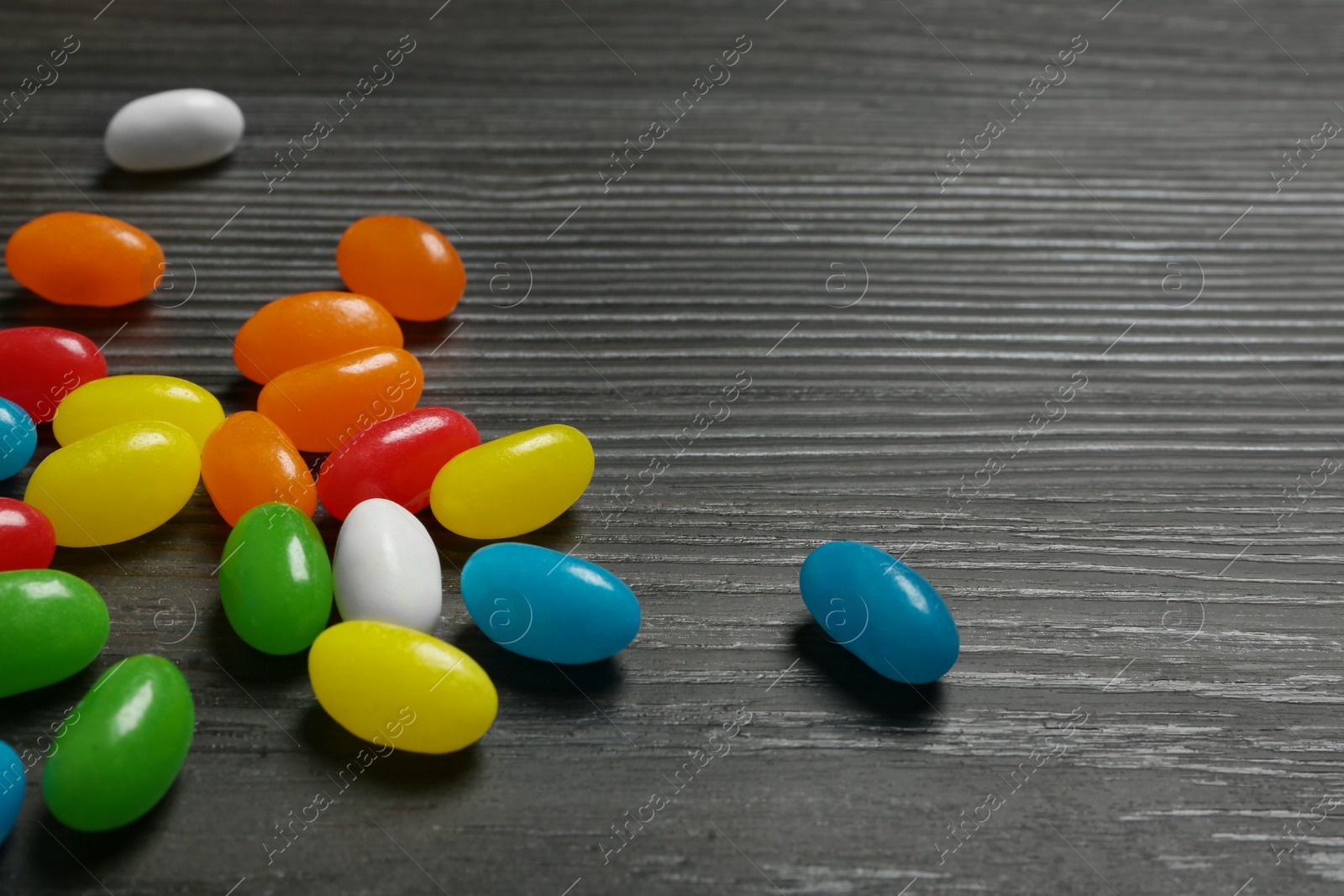 Photo of Delicious bright jelly beans on wooden background, closeup. Space for text