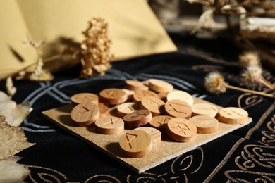 Photo of Many wooden runes and dried flowers on divination mat, closeup