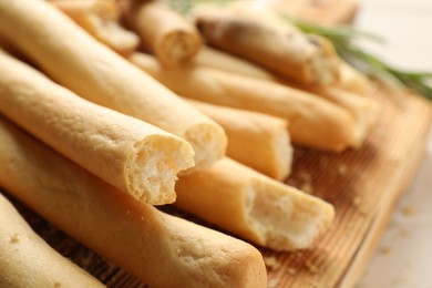 Delicious grissini sticks on wooden board, closeup