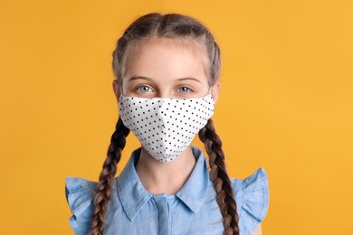 Photo of Girl wearing protective mask on yellow background. Child's safety from virus