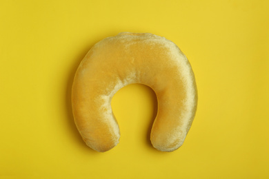 Photo of Soft travel pillow on yellow background, top view