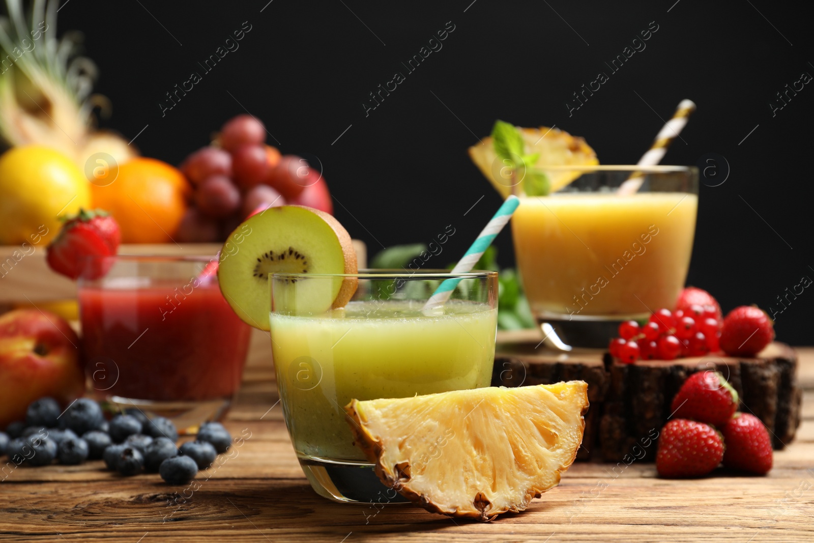 Photo of Delicious colorful juices in glasses and fresh ingredients on wooden table