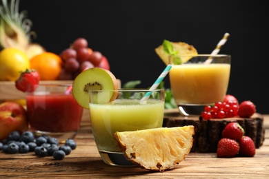 Photo of Delicious colorful juices in glasses and fresh ingredients on wooden table