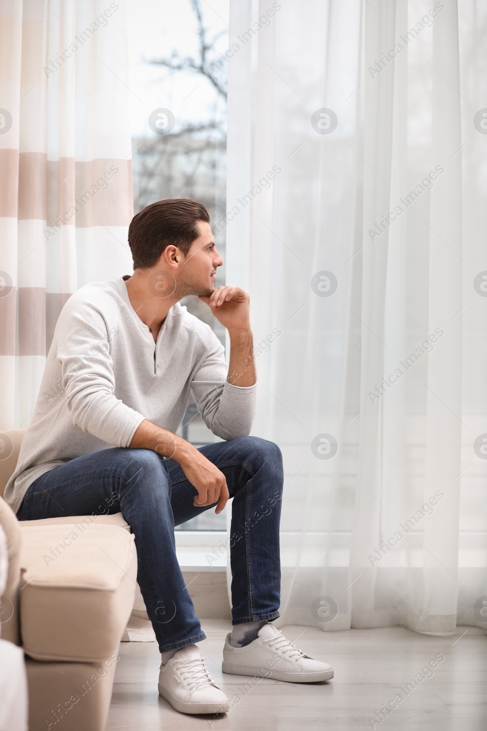 Photo of Handsome man resting on couch near window at home