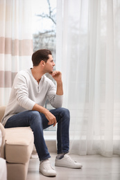 Photo of Handsome man resting on couch near window at home