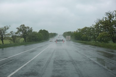 Photo of View of country road with cars on rainy day