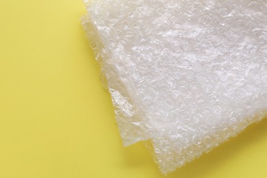 Photo of Transparent bubble wrap on yellow background, top view. Space for text